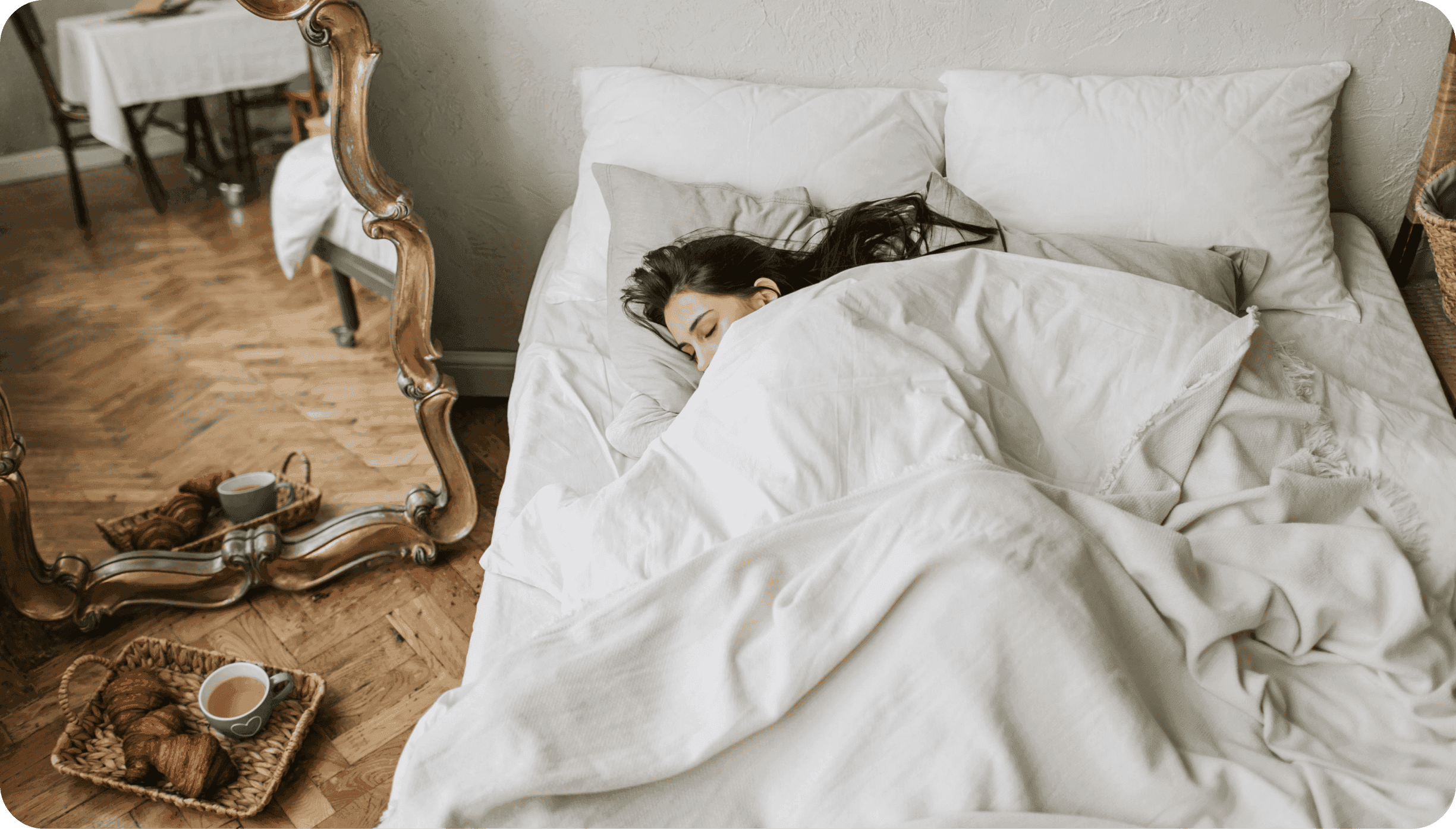 Vyhořelá žena ležící v posteli zakrytá peřinou.