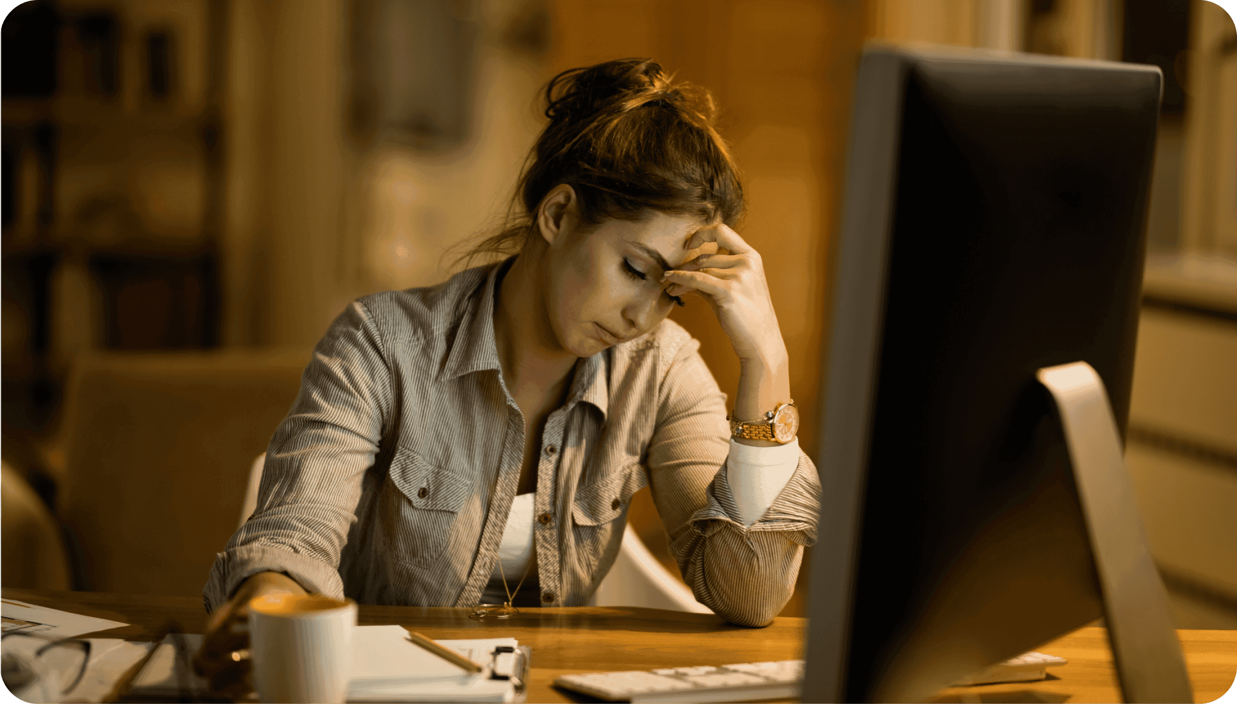 Unavená žena sedící za počítačem.